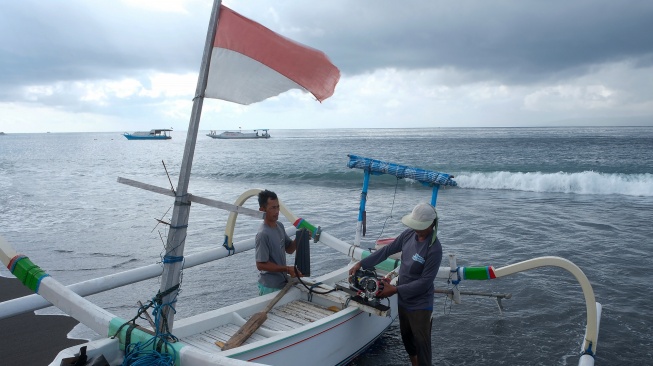 Dua nelayan memasang mesin propulsi listrik di perahu tradisional saat akan melaut di Pantai Segara Kusamba, Klungkung, Bali, Rabu (27/8/2025). [ANTARA FOTO/Nyoman Hendra Wibowo/bar]