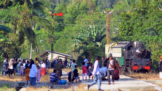Warga menyambut lokomotif E1060 Mak Itam saat membawa wisatawan di Stasiun Muaro Kalaban Sawahlunto, Sumatera Barat, Selasa (26/8/2025). [ANTARA FOTO/Iggoy el Fitra/nym]