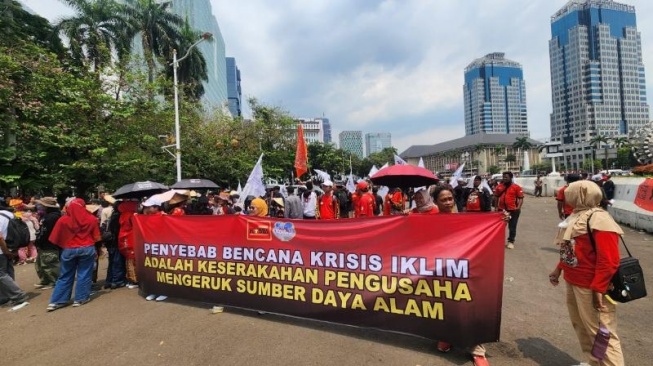Massa buruh menggelar aksi di area Patung Kuda di Jakarta, Kamis (28/8/2025). Mereka menyuarakan keadilan iklim. [Suara.com/Fakhri]