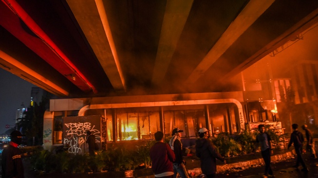 Pengunjuk rasa berada di samping halte Transjakarta yang dibakar saat aksi menuntut pengusutan kasus penabrakan pengemudi ojek daring oleh mobil rantis Brimob di depan Markas Komando Brimob Polda Metro Jaya, Kwitang, Jakarta, Jumat (29/8/2025). [ANTARA FOTO/Galih Pradipta/rwa]
