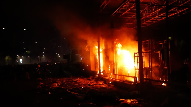 Pengunjuk rasa melihat Gerbang Tol Pejompongan yang dibakar saat aksi di Jakarta, Jumat (29/8/2025). [Suara.com/Alfian Winanto]
