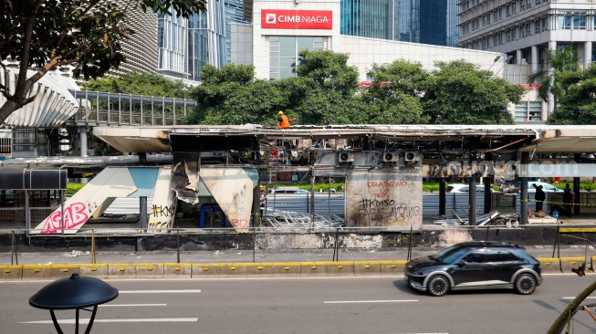 Petugas memperbaiki Halte Transjakarta Senayan pasca terbakar di Jakarta, Senin (1/9/2025). [Suara.com/Alfian Winanto]