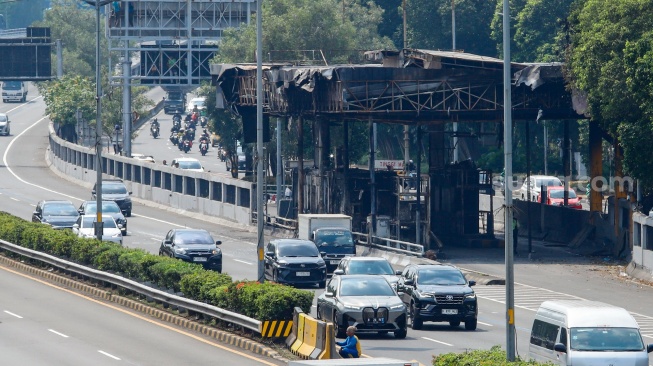 Kendaraan melintas di samping Gerbang Tol Pejompongan pasca terbakar di Jakarta, Senin (1/9/2025). [Suara.com/Alfian Winanto]