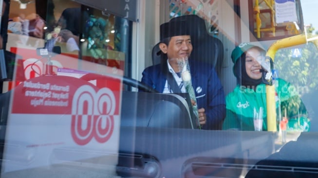 Pengemudi ojek online (ojol) membagikan bunga ke pengguna jalan saat aksi damai di Jalan Merdeka Selatan, Jakarta, Selasa (2/9/2025). [Suara.com/Alfian Winanto]