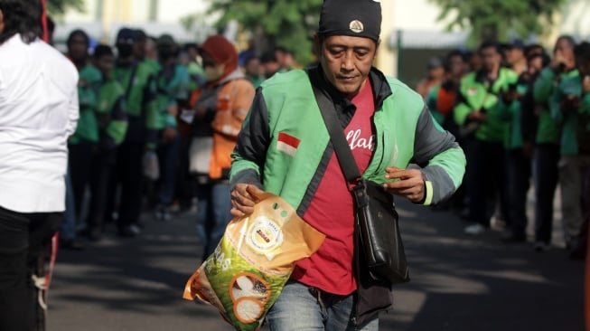 Pengemudi ojek online menerima bantuan beras seusai doa bersama di parkir timur GOR Delta Sidoarjo, Jawa Timur, Jumat (5/9/2025). [ANTARA FOTO/Umarul Faruq/YU]