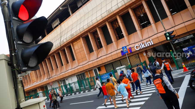Pejalan kaki menyeberang pada pelican crossing di depan Stasiun Cikini, Jakarta, Senin (15/9/2025). [Suara.com/Alfian Winanto]