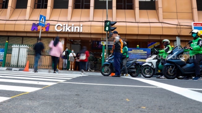 Pejalan kaki menyeberang pada pelican crossing di depan Stasiun Cikini, Jakarta, Senin (15/9/2025). [Suara.com/Alfian Winanto]