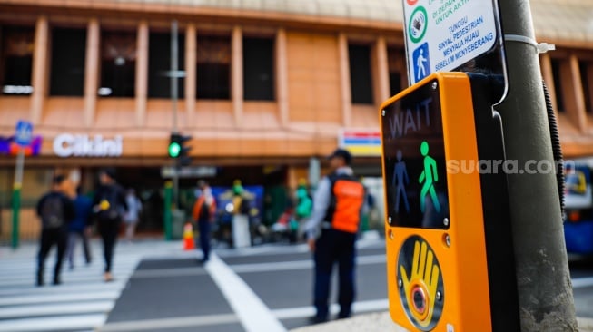 Pejalan kaki menyeberang pada pelican crossing di depan Stasiun Cikini, Jakarta, Senin (15/9/2025). [Suara.com/Alfian Winanto]