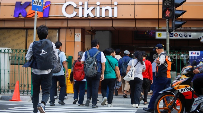 Pejalan kaki menyeberang pada pelican crossing di depan Stasiun Cikini, Jakarta, Senin (15/9/2025). [Suara.com/Alfian Winanto]