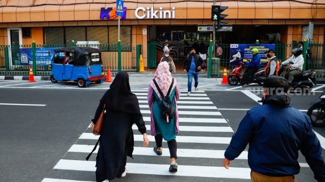 Pejalan kaki menyeberang pada pelican crossing di depan Stasiun Cikini, Jakarta, Senin (15/9/2025). [Suara.com/Alfian Winanto]