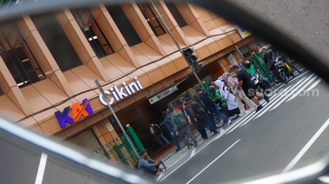 Pejalan kaki menyeberang pada pelican crossing di depan Stasiun Cikini, Jakarta, Senin (15/9/2025). [Suara.com/Alfian Winanto]