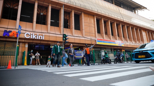 Pejalan kaki menyeberang pada pelican crossing di depan Stasiun Cikini, Jakarta, Senin (15/9/2025). [Suara.com/Alfian Winanto]