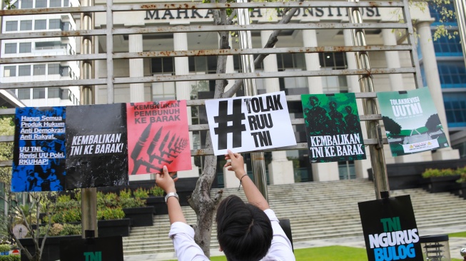 Peserta aksi yang tergabung dalam Koalisi Masyarakat Sipil Untuk Reformasi Sektor Keamanan mengangkat poster saat mengikuti aksi di depan Gedung Mahkamah Konstitusi (MK), Jakarta, Rabu (17/9/2025). [Suara.com/Alfian Winanto]