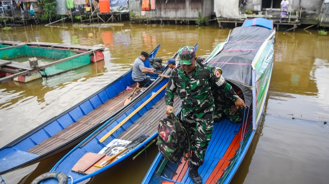 Prajurit TNI AD anggota Kodim 0906/Kutai Kartanegara, Peltu Suhendro berjalan dari perahu klinik terapung saat akan melakukan pemeriksaan kesehatan warga di kawasan Loa Ipuh, Tenggarong, Kutai Kartanegara, Kalimantan Timur, Jumat (19/9/2025). [ANTARA FOTO/M Risyal Hidayat/tom]