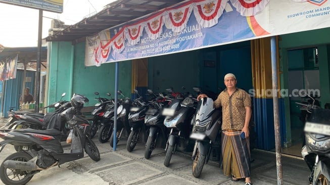 Muhari berdiri di depan usaha jual beli motornya yang berada di Kotagede, Yogyakarta. (Suara.com/Irwan Febri)