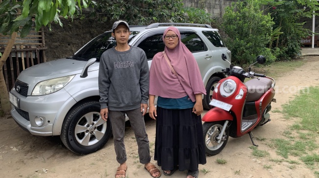 Slamet Hadi Mulyono (kiri) dan sang istri Nani Sukowati (kanan) berdiri di depan mobil dan motor hasil usaha gilingan, Kamis (18/9/2025). (Suara.com/Irwan Febri)