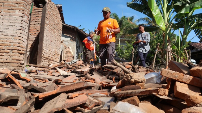 Petugas BPBD mengukur luasan bangunan yang ambruk akibat gempa di Desa Bimorejo, Wongsorejo, Banyuwangi, Jawa Timur, Jumat (26/9/2025). [ANTARA FOTO/Budi Candra Setya/bar]