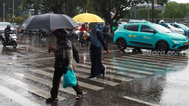 Pejalan kaki menggunakan payung saat hujan di Kawasan Slipi, Jakarta, Senin (29/9/2025). [Suara.com/Alfian Winanto]