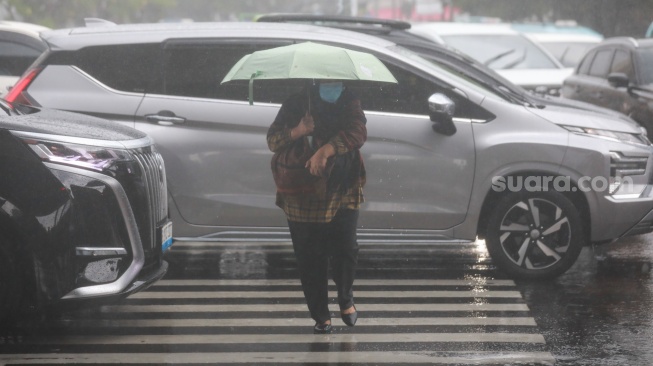 Pejalan kaki menggunakan payung saat hujan di Kawasan Slipi, Jakarta, Senin (29/9/2025). [Suara.com/Alfian Winanto]