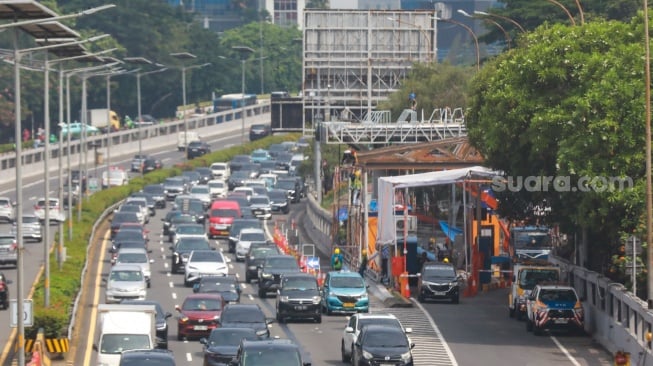 Pekerja menyelesaikan proyek perbaikan Gerbang Tol Pejompongan, Jakarta, Selasa (30/9/2025). [Suara.com/Alfian Winanto]