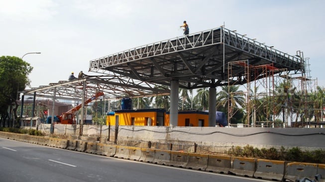 Pekerja menyelesaikan proyek perbaikan Gerbang Tol Pejompongan, Jakarta, Selasa (30/9/2025). [Suara.com/Alfian Winanto]