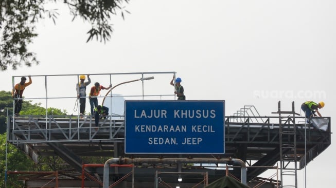 Pekerja menyelesaikan proyek perbaikan Gerbang Tol Pejompongan, Jakarta, Selasa (30/9/2025). [Suara.com/Alfian Winanto]