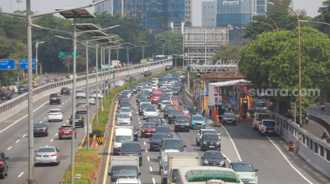Pekerja menyelesaikan proyek perbaikan Gerbang Tol Pejompongan, Jakarta, Selasa (30/9/2025). [Suara.com/Alfian Winanto]