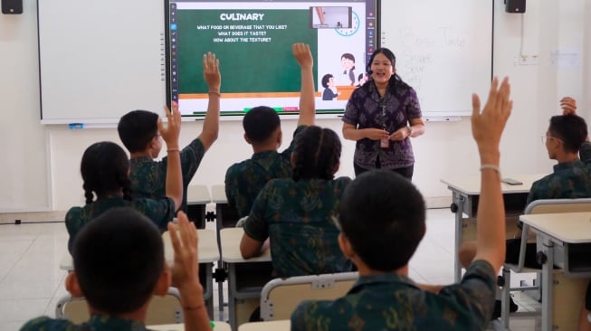 Seorang guru memberikan penjelasan kepada siswa yang mengikuti pelajaran bahasa inggris dengan metode pembelajaran smart classroom atau ruang kelas pintar di SMP Negeri 15 Denpasar, Bali, Jumat (3/10/2025). [ANTARA FOTO/Nyoman Hendra Wibowo/YU]