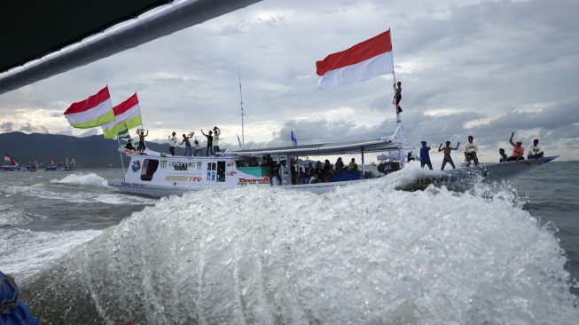 Sejumlah warga berada di atas kapal nelayan berhias bendera berkeliling saat mengikuti pesta nelayan di kawasan Pantai Kasiwa, Mamuju, Sulawesi Barat, minggu (5/10/2025). [ANTARA FOTO/Akbar Tado/foc]