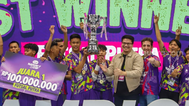 Ketua Umum Federasi Futsal Indonesia Michael Sianipar (ketiga kanan) didampingi Chief Marketing Officer XLSMART Alfons Bosch Sansa (kedua kanan) menyerahkan piala kepada tim futsal putra SMK Nusantara Jakarta Barat sebagai juara pertama AXIS Nation Cup (ANC) 2025 di Istora Senayan, Jakarta, Sabtu (11/10/2025). [Suara.com/Alfian Winanto]