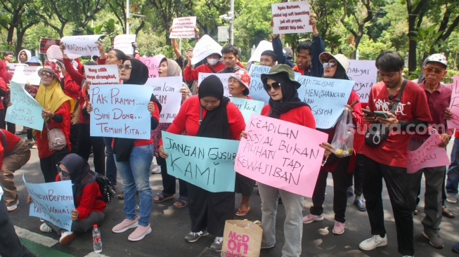 Sejumlah pedagang Pasar Hewan Barito membawa poster saat berunjuk rasa di depan Balai Kota DKI Jakarta, Selasa (14/10/2025). [Suara.com/Alfian Winanto]
