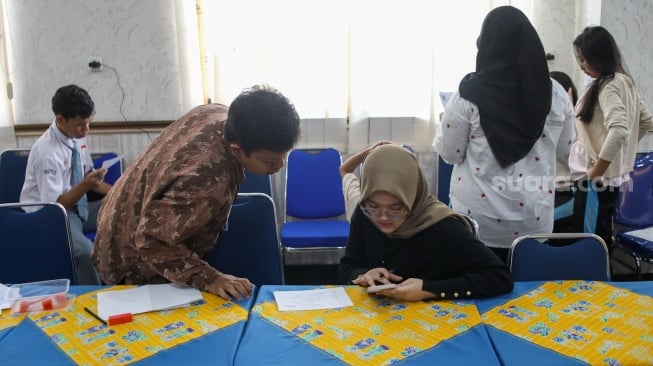 Petugas dari Dinas Kependudukan dan Pencatatan Sipil (Disdukcapil) DKI Jakarta melakukan perekaman e-KTP di SMKN 32 Jakarta, Kamis (16/10/2025). [Suara.com/Alfian Winanto]