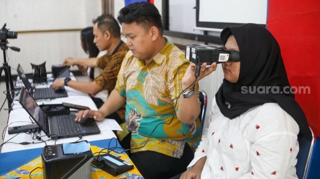 Petugas dari Dinas Kependudukan dan Pencatatan Sipil (Disdukcapil) DKI Jakarta melakukan perekaman e-KTP di SMKN 32 Jakarta, Kamis (16/10/2025). [Suara.com/Alfian Winanto]