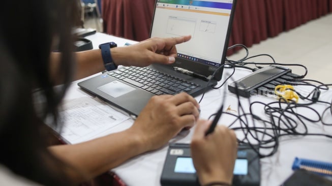 Petugas dari Dinas Kependudukan dan Pencatatan Sipil (Disdukcapil) DKI Jakarta melakukan perekaman e-KTP di SMKN 32 Jakarta, Kamis (16/10/2025). [Suara.com/Alfian Winanto]
