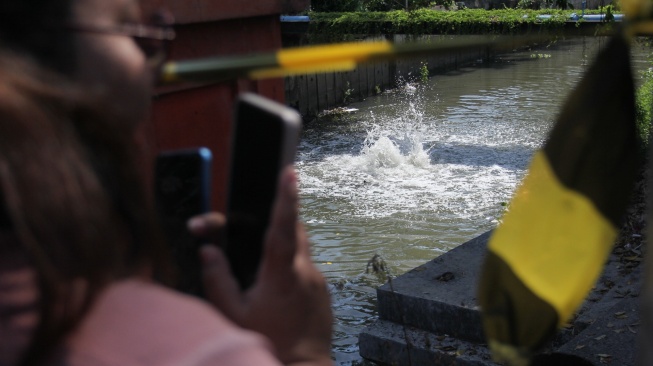 Warga merekam gelembung-gelembung yang keluar dari sungai di kawasan Rungkut Mapan, Surabaya, Jawa Timur, Jumat (17/10/2025). [ANTARA FOTO/Didik Suhartono/foc]