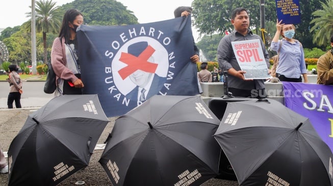 Massa dari Koalisi Bersihkan Indonesia (KBI) saat menggelar aksi simbolik di Taman Pandang Istana, Jakarta, Senin (20/10/2025). [Suara.com/Alfian Winanto]