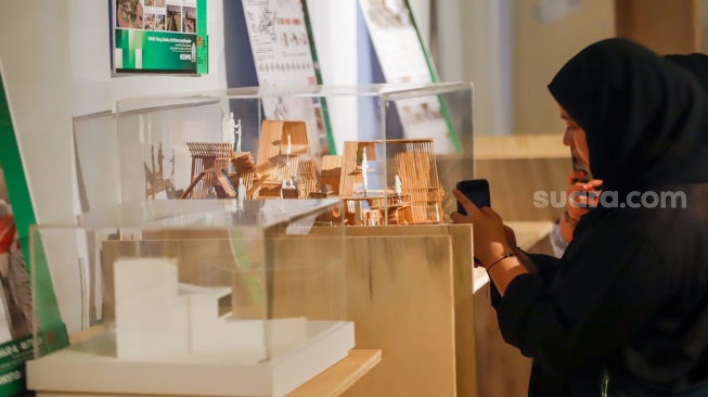 Pengunjung mengamati instalasi maket bangunan dalam Jakarta Architecture Festival 2025 di Blok M Hub, Jakarta, Kamis (23/10/2025). [Suara.com/Alfian Winanto]