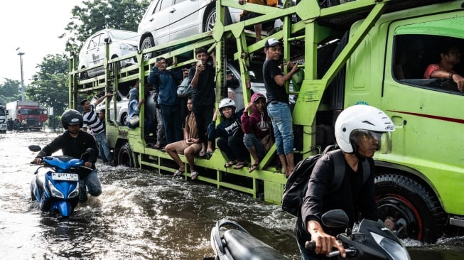 Sejumlah warga menumpang truk untuk dapat menembus banjir yang menggenangi jalur utama pantura Semarang-Surabaya di Jalan Kaligawe Raya, Semarang, Jawa Tengah, Jumat (24/10/2025). [ANTARA FOTO/Aprillio Akbar/YU]