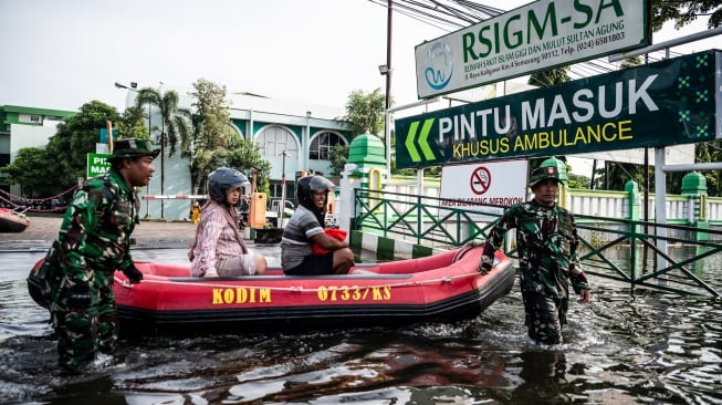 Personel Babinsa Koramil 06/Genuk menggunakan perahu karet untuk mengangkut pasien saat banjir melanda jalur utama Pantura Semarang - Surabaya di Jalan Kaligawe Raya, Semarang, Jawa Tengah, Jumat (24/10/2025). [ANTARA FOTO/Aprillio Akbar/YU]