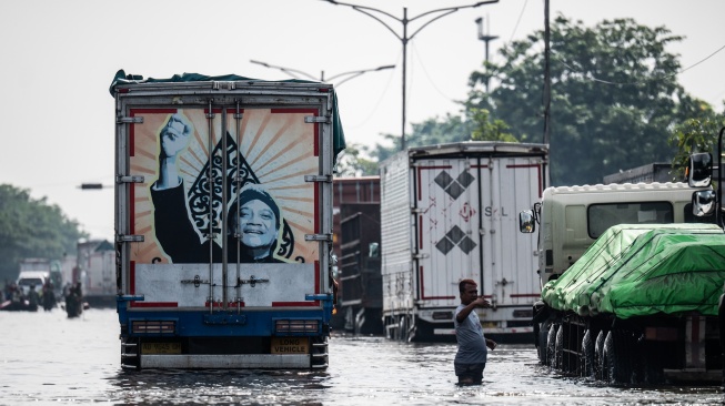 Warga mengatur arus lalu lintas saat banjir menggenangi jalur utama pantura Semarang-Surabaya di Jalan Kaligawe Raya, Semarang, Jawa Tengah, Jumat (24/10/2025). [ANTARA FOTO/Aprillio Akbar/YU]