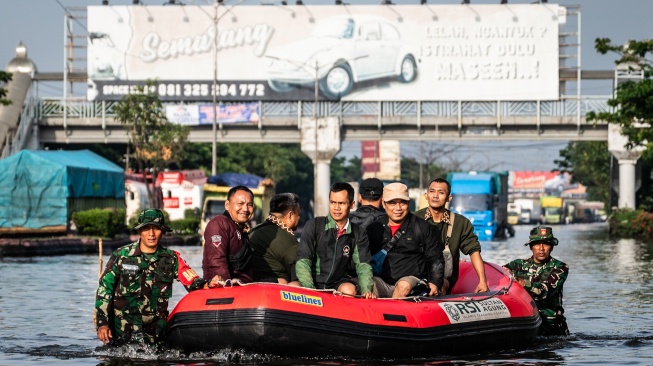 Personel Babinsa Koramil 06/Genuk menggunakan perahu karet untuk mengangkut pasien dan tenaga kesehatan saat banjir melanda jalur utama Pantura Semarang - Surabaya di Jalan Kaligawe Raya, Semarang, Jawa Tengah, Jumat (24/10/2025). [ANTARA FOTO/Aprillio Akbar/YU]