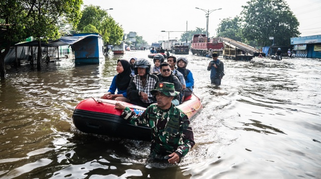 Personel Babinsa Koramil 06/Genuk menggunakan perahu karet untuk mengangkut pasien dan tenaga kesehatan saat banjir melanda jalur utama Pantura Semarang - Surabaya di Jalan Kaligawe Raya, Semarang, Jawa Tengah, Jumat (24/10/2025). [ANTARA FOTO/Aprillio Akbar/YU]