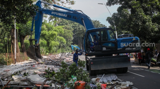 Petugas membongkar kios menggunakan eskavator di Pasar Hewan Barito, Jakarta, Senin (27/10/2025). [Suara.com/Alfian Winanto]