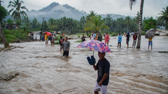 Warga melintasi lahar hujan Gunung Semeru yang meluap dari Sungai Regoyo di Desa Gondoruso, Kecamatan Pasirian, Lumajang, Jawa Timur, Rabu (5/11/2025). [ANTARA FOTO/Irfan Sumanjaya/nym]