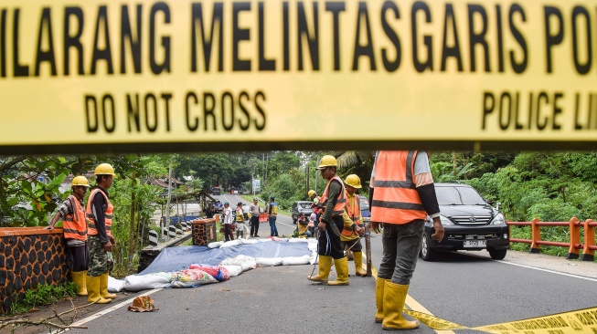Pekerja menutup material tanah longsor menggunakan terpal di Jembatan Cikaleho, Kecamatan Cipaku, Kabupaten Ciamis, Jawa Barat, Sabtu (8/11/2025). [ANTARA FOTO/Adeng Bustomi/rwa]