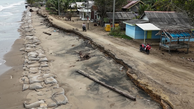 Foto udara pengendara sepeda motor melintas di atas badan jalan yang amblas tergerus abrasi pantai di Desa Lhok Puuk, Seunudon, Aceh Utara, Aceh, Sabtu (8/11/2025). [ANTARA FOTO/Syifa Yulinnas/rwa]
