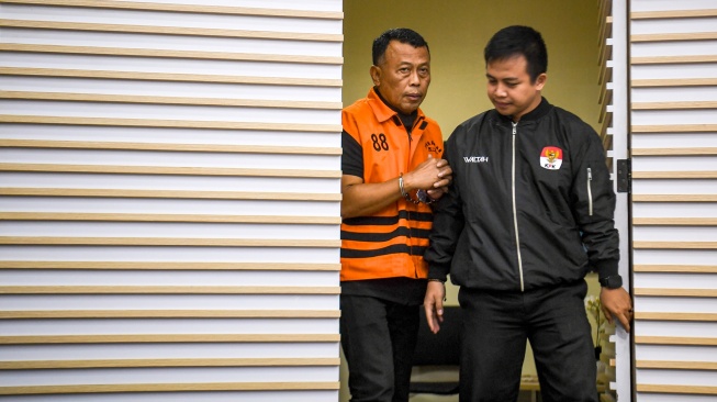 Petugas membawa tersangka selaku Bupati Ponorogo Sugiri Sancoko (kiri) untuk dihadirkan dalam konferensi pers di gedung Merah Putih KPK, Jakarta, Minggu (9/11/2025). [ANTARA FOTO/Muhammad Adimaja/sgd]