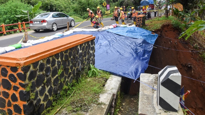 Pekerja menutup material tanah longsor menggunakan terpal di Jembatan Cikaleho, Kecamatan Cipaku, Kabupaten Ciamis, Jawa Barat, Sabtu (8/11/2025).[ANTARA FOTO/Adeng Bustomi/rwa]
