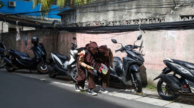 Warga beraktivitas di dekat jaringan kabel utilitas yang menjuntai di kawasan Setiabudi, Jakarta, Rabu (12/11/2025). [Suara.com/Alfian Winanto]