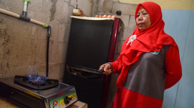 Warga memasak menggunakan kompor biogas saat peresmian pemanfaatan biogas melalui instalasi tangki septik komunal oleh Gubernur DKI Jakarta Pramono Anung di permukiman Gang Delta, Pekayon, Pasar Rebo, Jakarta Timur, Kamis (13/11/2025). [ANTARA FOTO/Indrianto Eko Suwarso/bar]